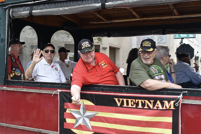 Members of Vietnam Brotherhood, riding on a trolley, greet the crowd.