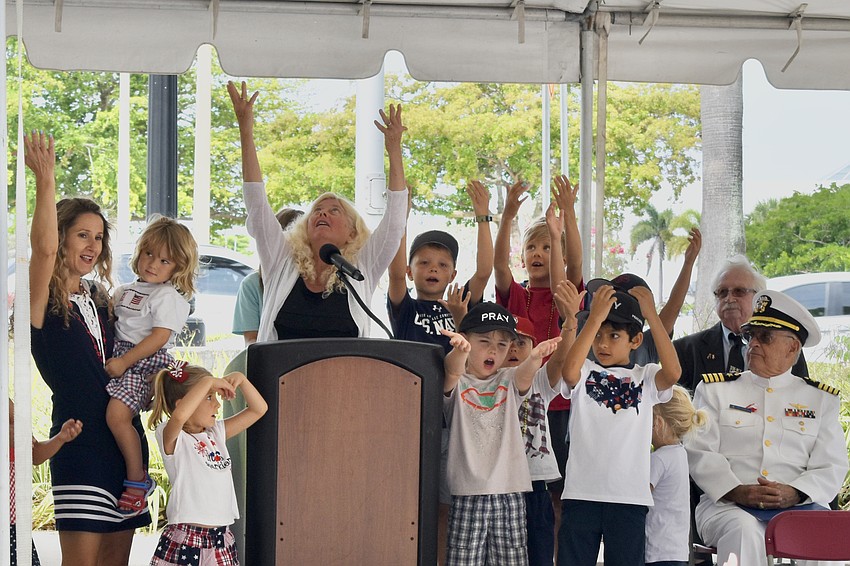 Jan Hamel Solomon of Sailing Home Sarasota leads the children at the ceremony in an invitation to the public, in English and Spanish.