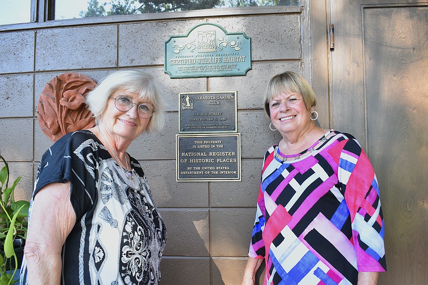 Vice President CJ Danna and Historian Olivia Haynes stand beside the building's three plaques, which indicate a national certifiation as a wildlife habitat and historical designations at the city and national level.