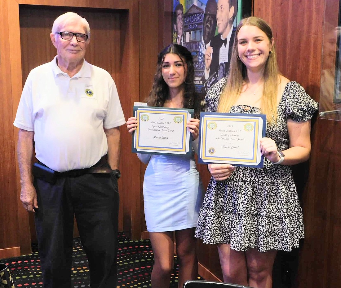 Hank Lunsford, president of the Ormond Beach Lions Club, withYouth Exchange Scholarship recipients Paula Telles and Alyssa Capel.