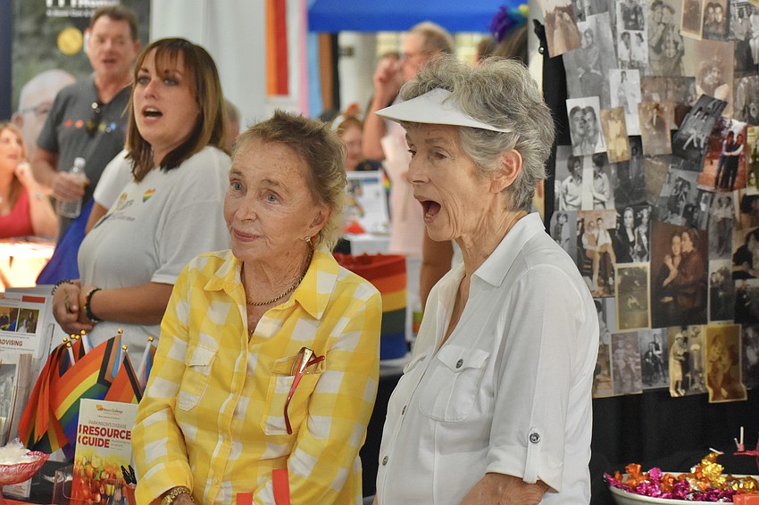 Pauline Tondreau and Mary Cumisay listen to an announcement, as Mary Cumisay shouts along with the group.