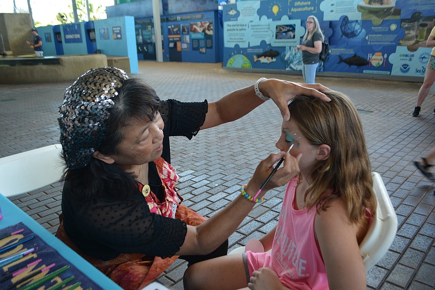 Akiko Campbell, face painter, paints Blair Lee's, 8, face.