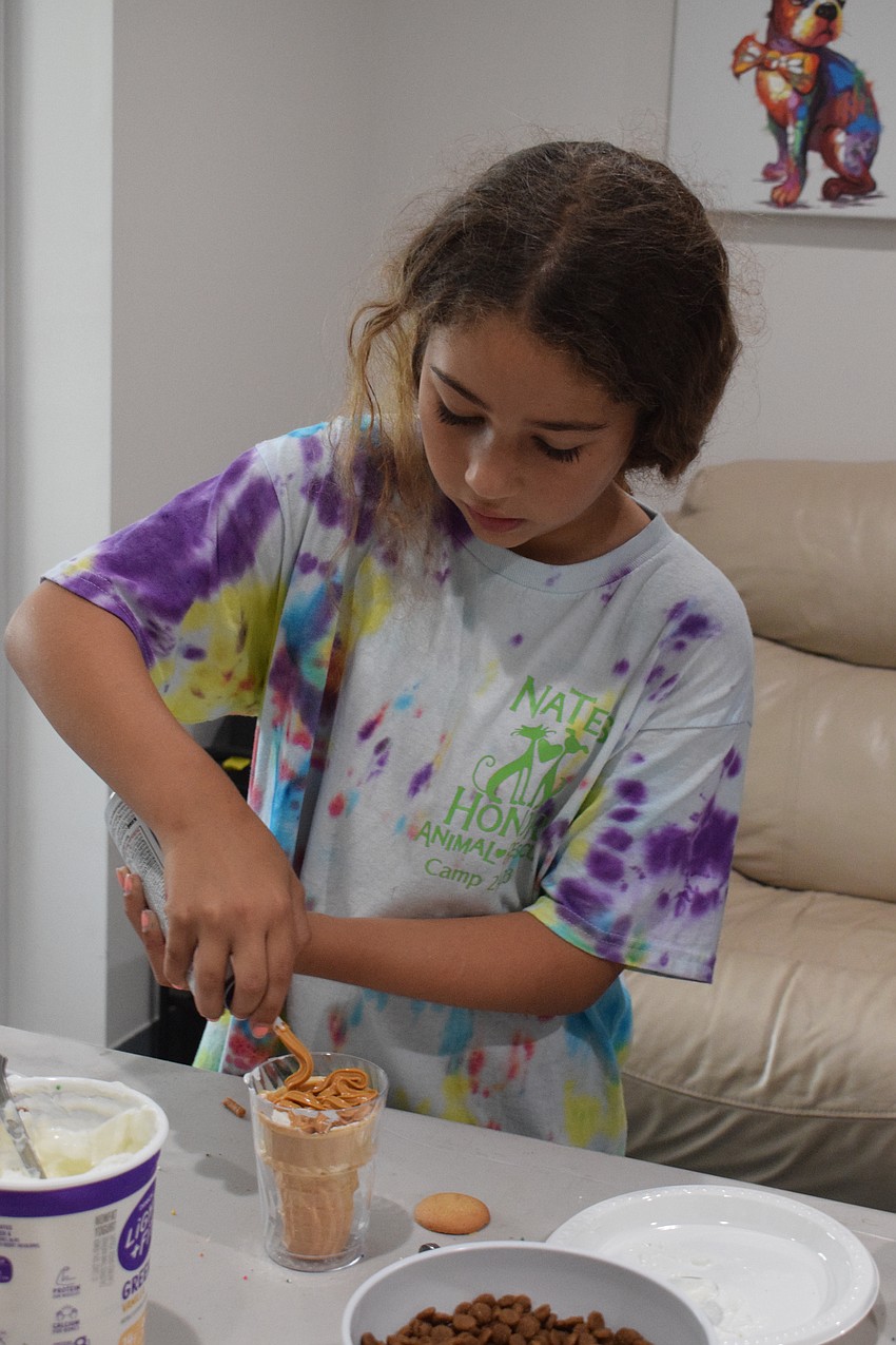 Olivia Mendez, who is 9, adds cheese as the final touch to her sundae for the dogs.