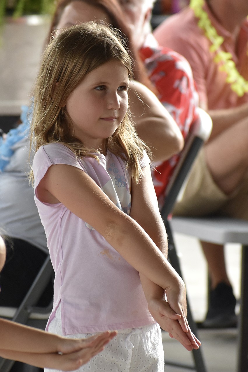 6-year-old Lydia Johnson mimics the motions of the Polynesian dancers after being among those selected to accompany them.