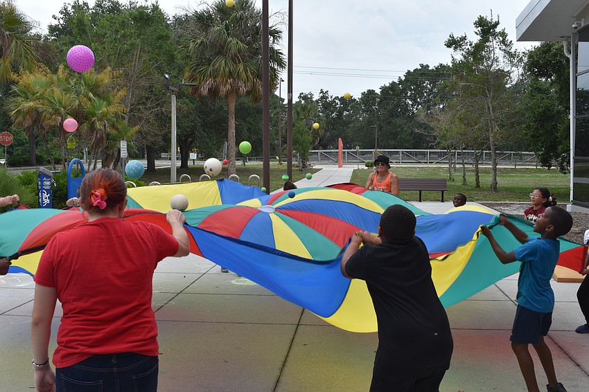 Kids from Boys & Girls Clubs of Sarasota and DeSoto Counties perform outdoor activities at the library during the barbecue event on June 16, led by Amy Raspiller of Amy's Hoop Circle.
