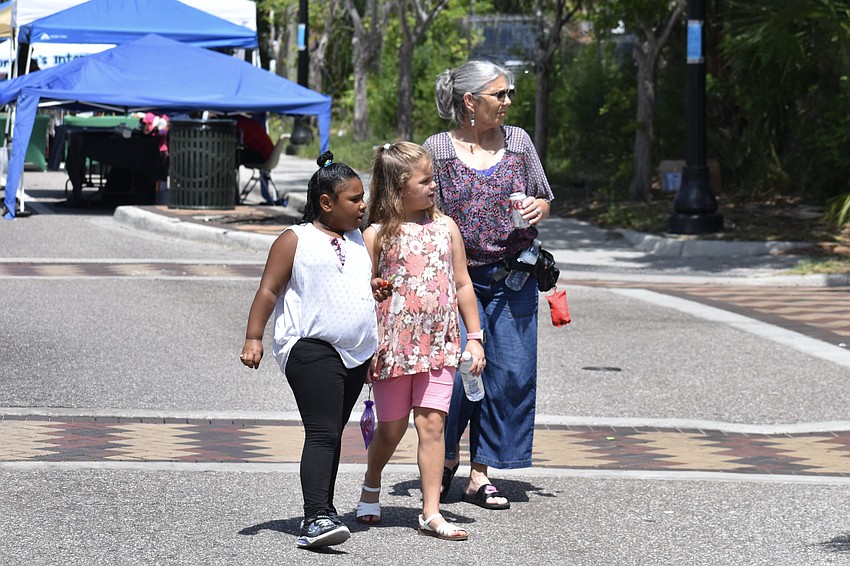 7-year-old Skyler Wade, 8-year-old Aubrie Stilwell and Lisa Gilbert explore the stands along the road.