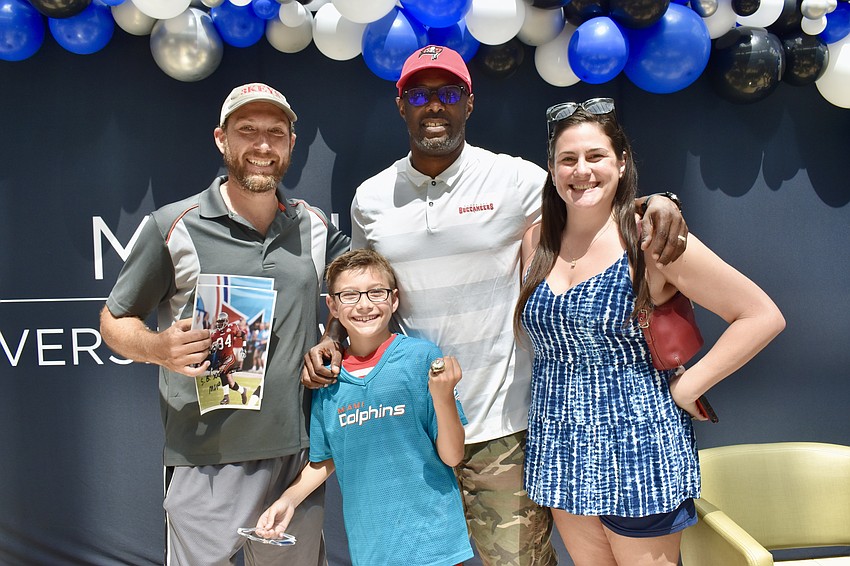 Summerfield residents Nick, Alessandro and Annya Hernandez pose with Super Bowl  XXXVII MVP Dexter Jackson, who let Alessandro try on his Super Bowl ring.