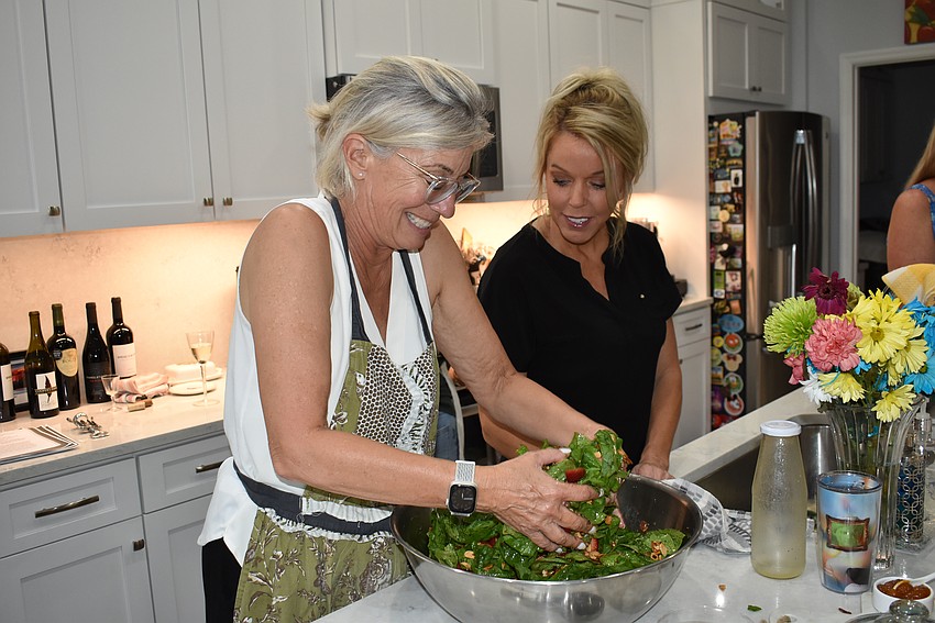 Susan Hanus tosses the salad with Julie Benjamin.