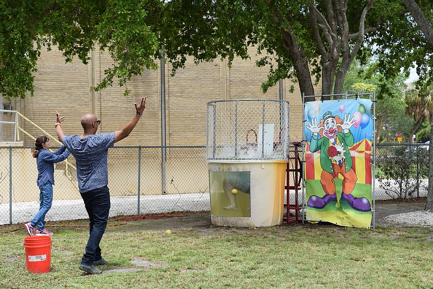 Barry Gaines aims perfectly to dunk people in the dunk tank while other employees cheer around him.