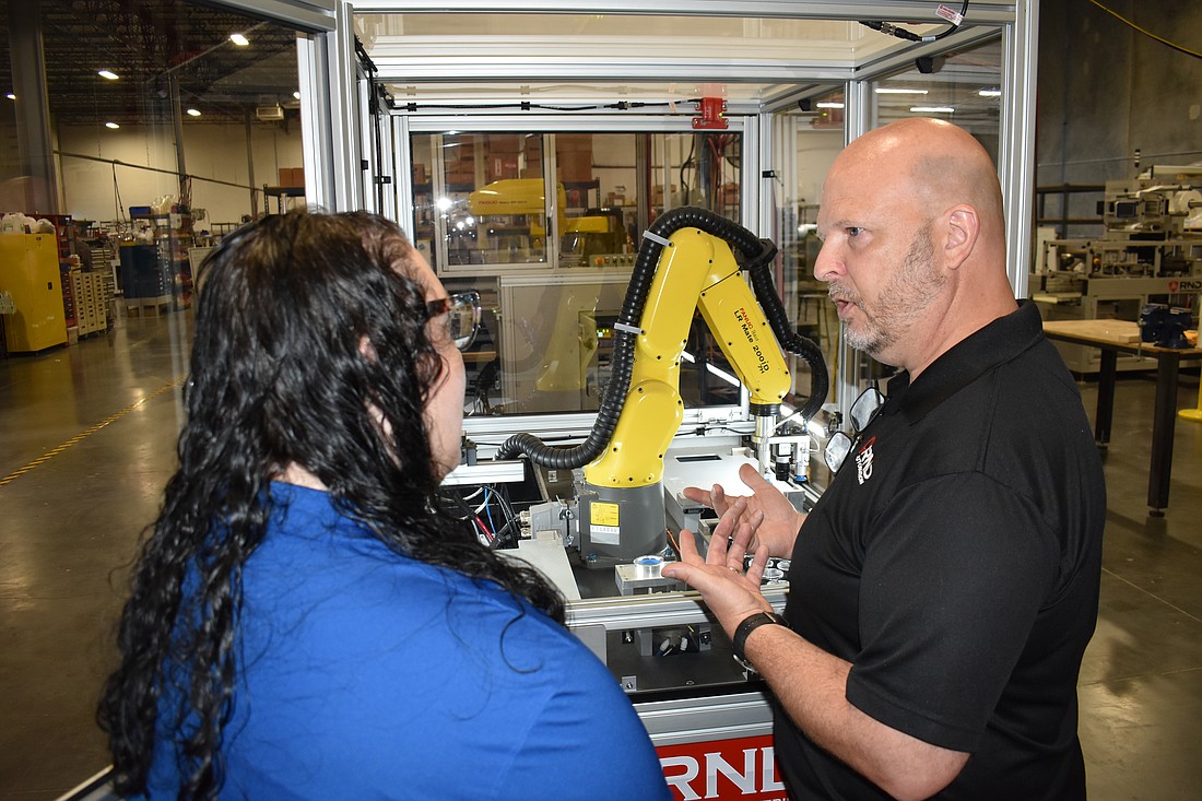 Heather Zahory of the Packaging Machinery Manufacturers Institute and RND Automation's Aaron Laine talk about an RND Automation machine that is being donated to SCF.