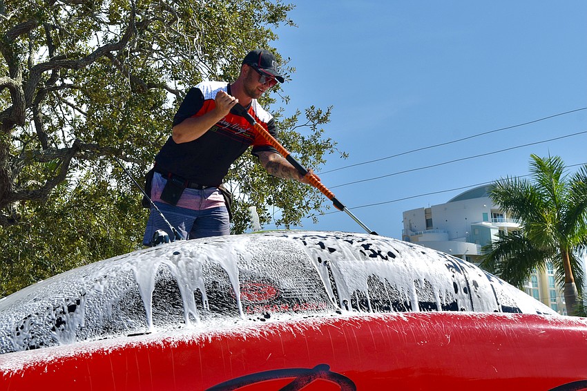 Adam Hindman, owner of the business Curb Appeal Auto & Marine Detailing, cleans the Waves and Wheels / Doug Wright boat after the race.