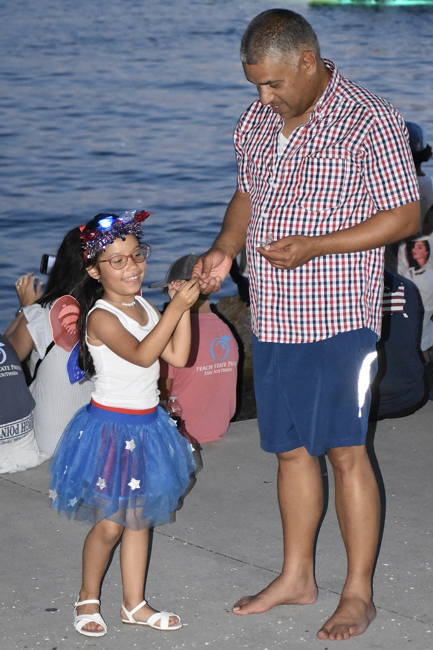 5-year-old Avril Baute accepts a noisemaking ball from Jose Baute.