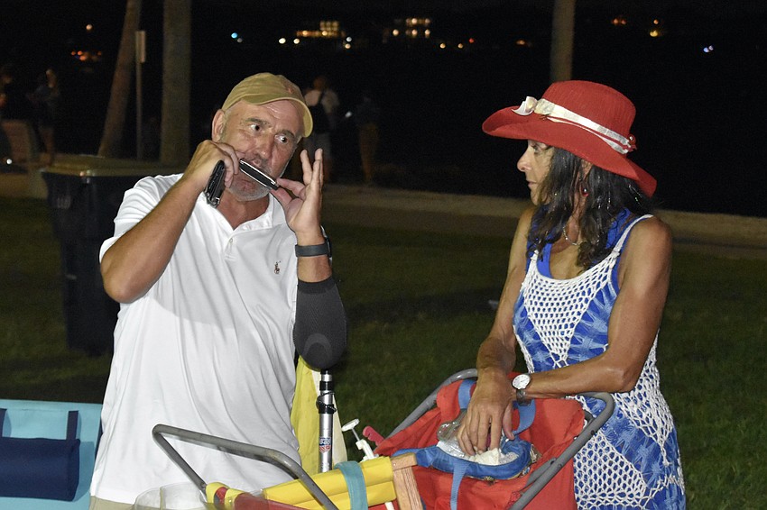 Rob Schmidt plays the harmonica as Ruth Weisberg watches.