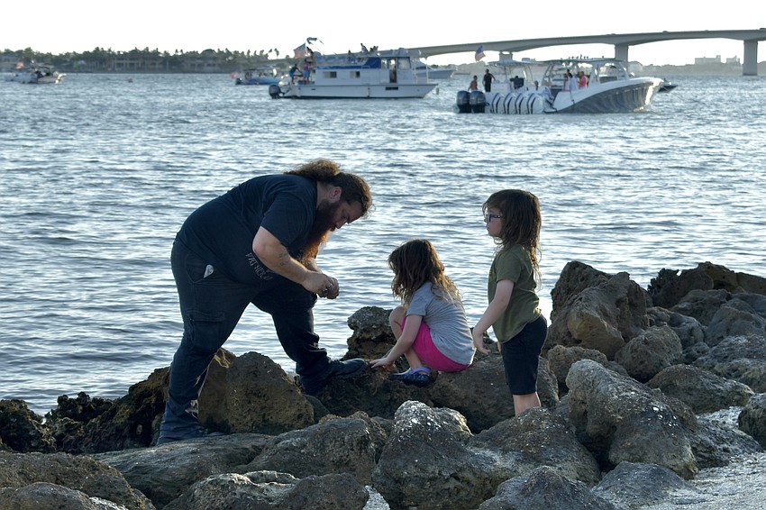Pablo Gueker, 8-year-old Quinn Gueker and 6-year-old Odyn Gueker explore the rocks at the shore.