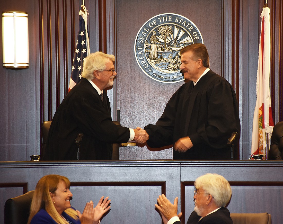 4th Judicial Circuit Chief Judge Lance Day, right, shakes hands with his predecessor, Mark Mahon, at the Passing of the Gavel cermony June 27 at the Duval County Courthouse. In front are 4th Circuit Trial Court Administrator Eve Janoko and Chief Technology Officer Mike Smith.