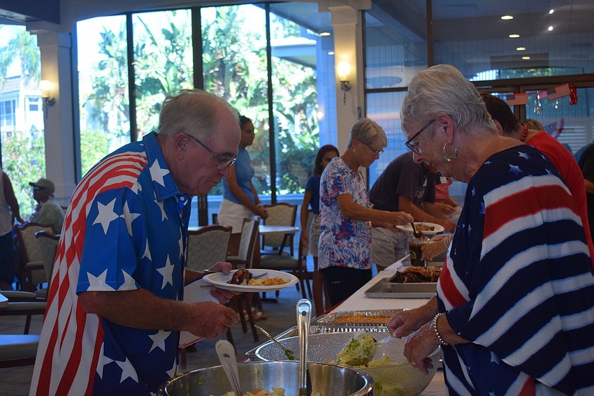 Carol Pacheco serves Gregory Bodkin delicious food at the Longboat Harbour Fourth of July party.