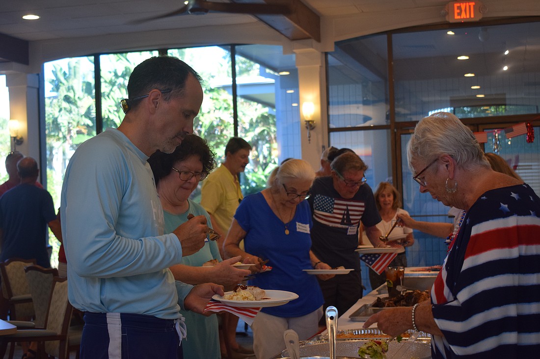 Residents and visitors of Longboat Harbour enjoy food at their Fourth of July party.