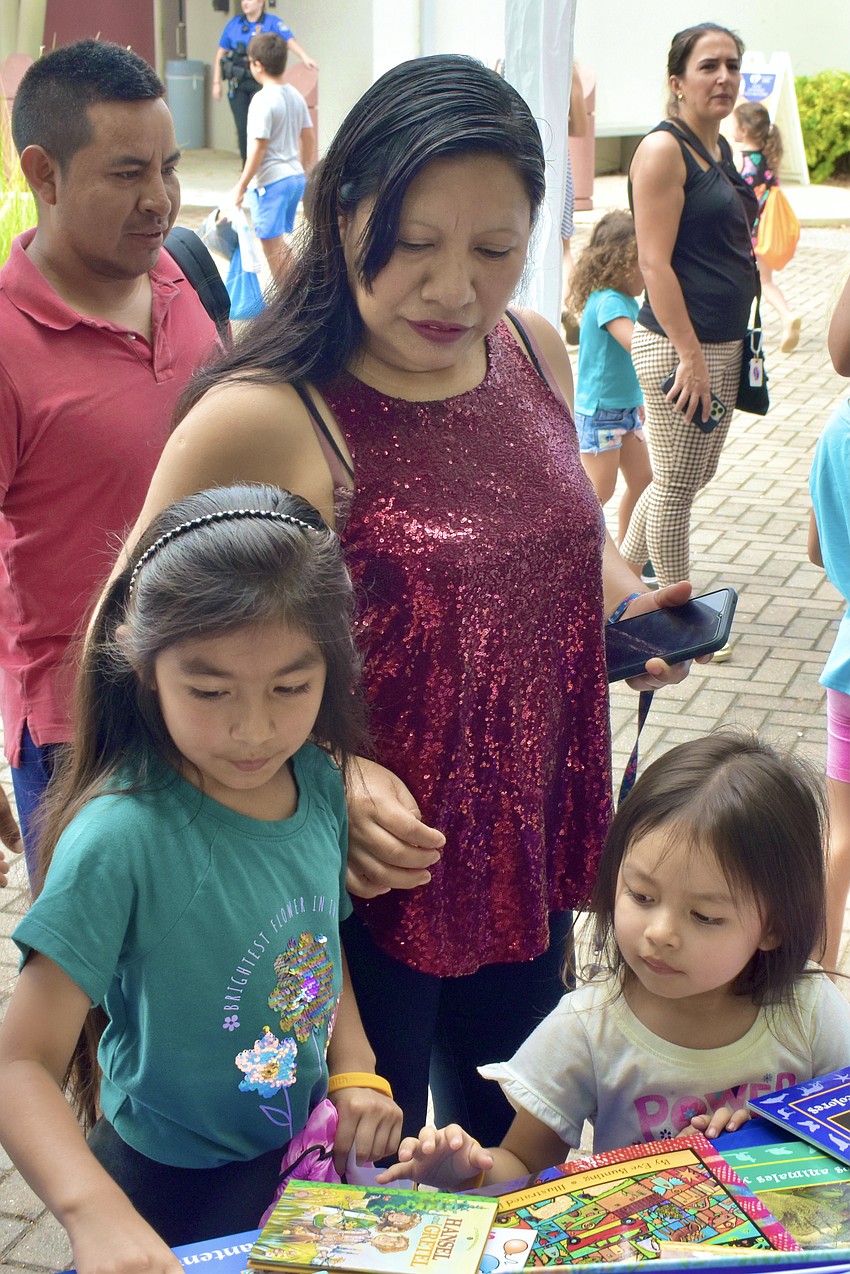 Carlos Perez, 6-year-old Jessica Perez-Lopez, Esperanza Lopez, and 4-year-old Kathy Perez-Lopez explore the books available.