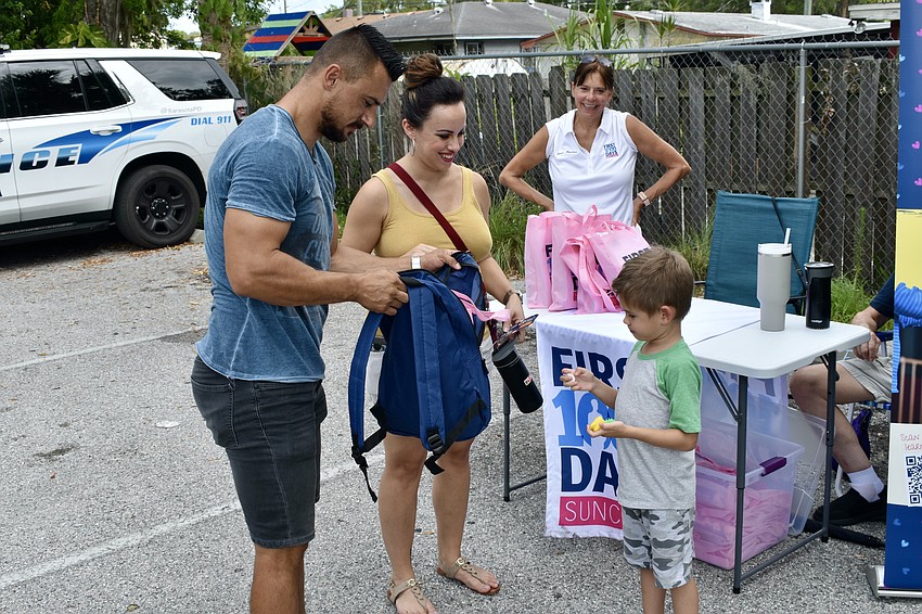 Zolee and Lauren Ambrus, and Janice Houchins of First 1000 Days Suncoast, watch as 5-year-old Josiah Ambrus examines some of the items he has received.