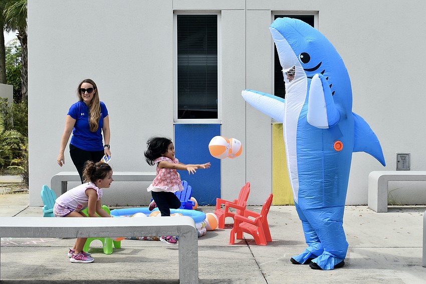 CenterPlace Health employee Shannon Carrasco and 7-year-old Kennedy Konen watch as 2-year-old Lorelay Enriquez tosses a ball towards Abi Valez, who is dressed as a shark.