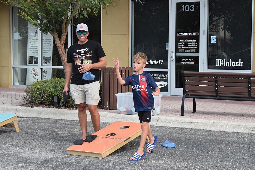Greyhawk Landing's Jake Zeitler watches his 7-year-old Calum Zeitler try to get a bag into the hole while playing cornhole. When Calum Zeitler does, he throws his hands up and yells in celebration.
