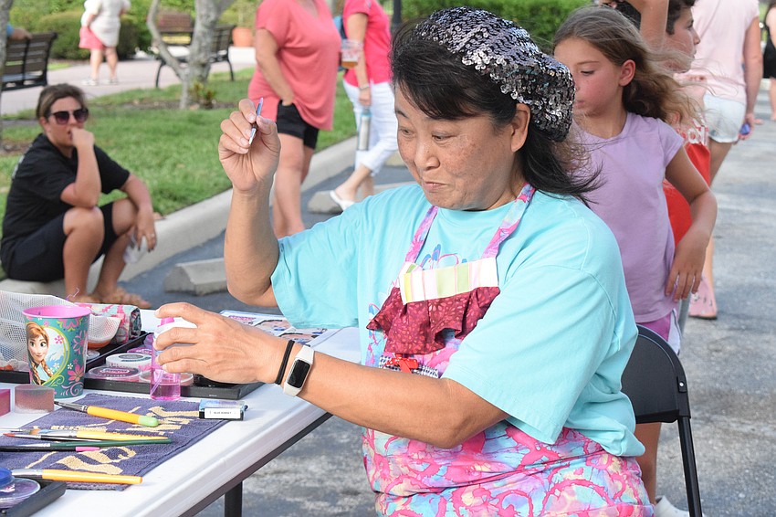 Akiko Campbell paints dozens of children's faces with various colorful designs.