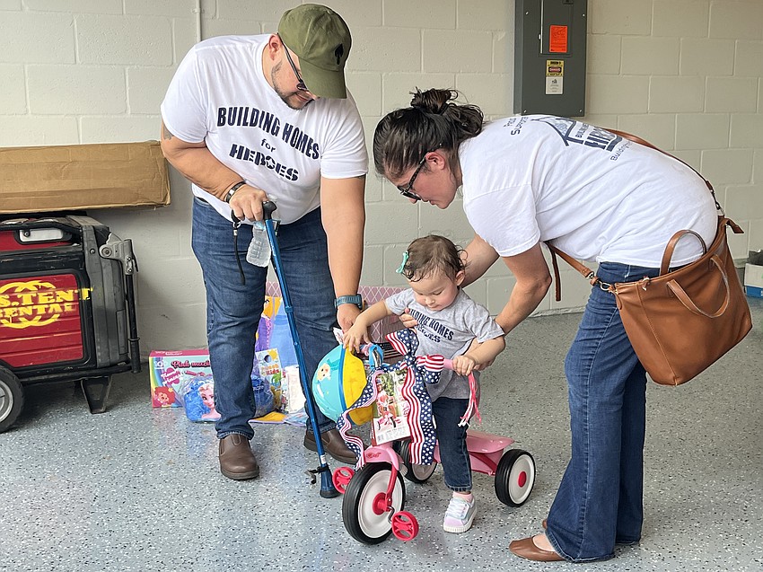 Army Sgt. Lucio Gaytan and his wife, Ivette Gaytan, help their 1-year-old daughter Lyanna Gaytan play with the toys that came with their new home.