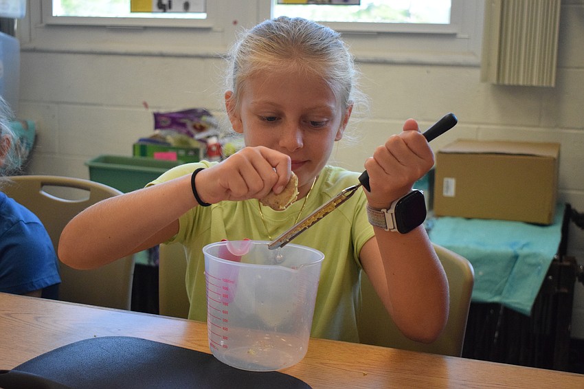 Paige Royce, a rising fourth grader, smells the ginger before grating it.