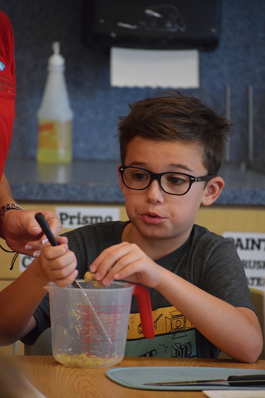 Graham Lough, a rising fourth grader, takes his time grating ginger so it can be added to the potsticker filling.