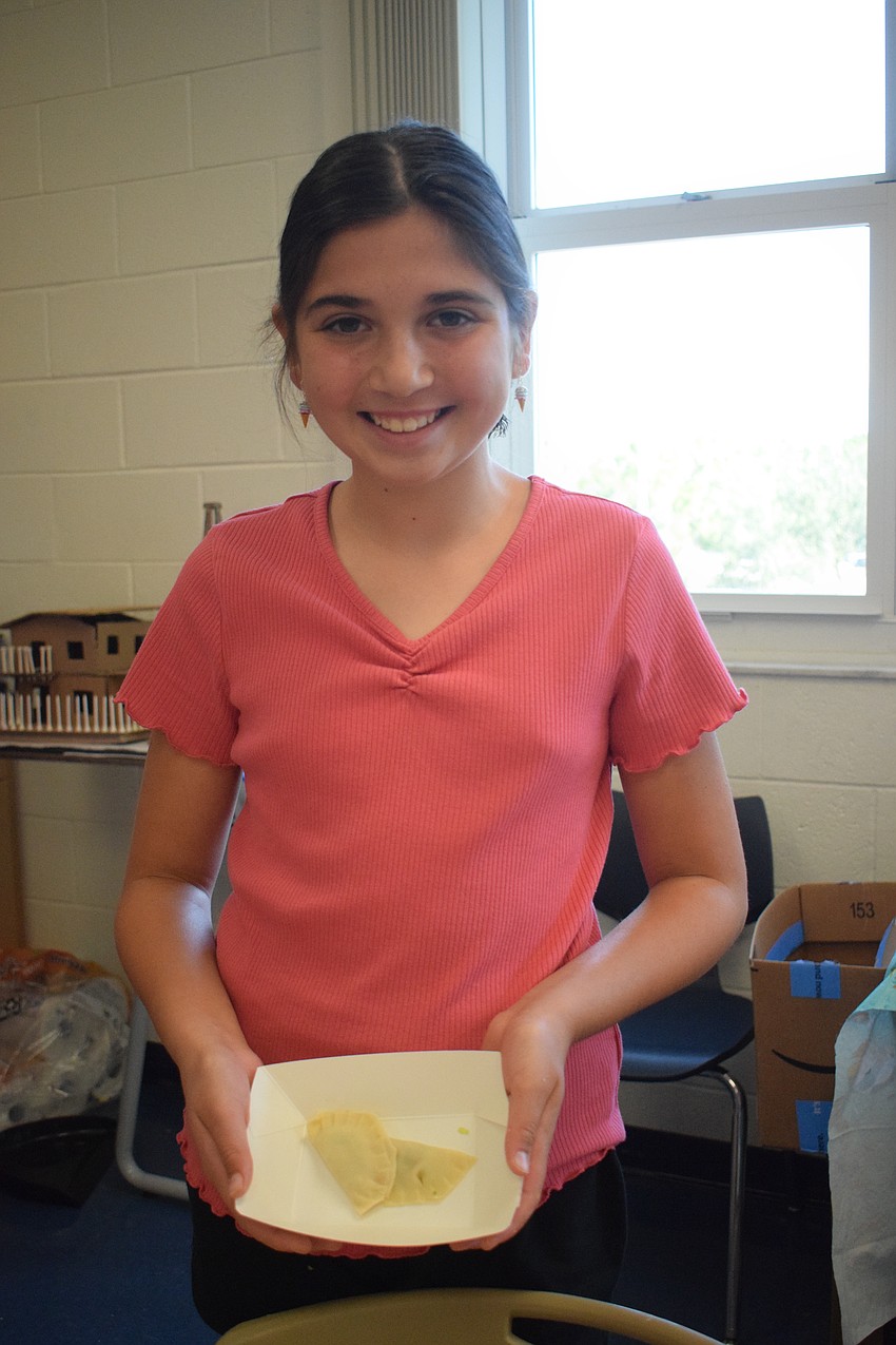 Payton Campbell, a rising fifth grader, shows off her finished potstickers as she makes her way to get them fried.
