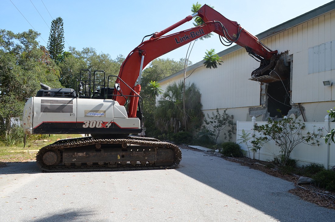 A trackhoe, piloted by Sarasota Mayor Kyle Battie, takes the first chunks out of the old Bath & Racquet Club.