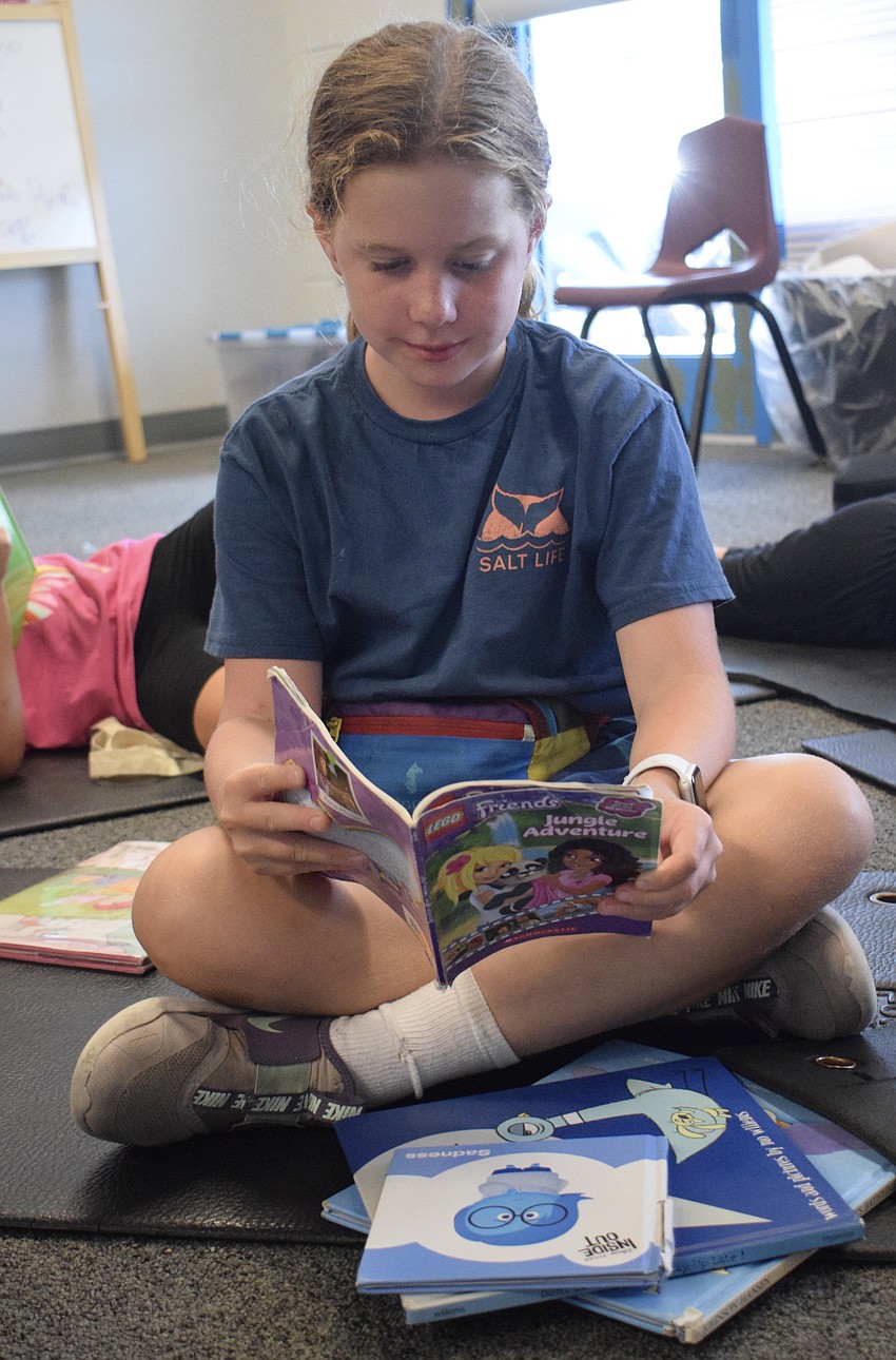 Brooklyn Cutsinger, who is 8, reads one book after the other at the YMCA Summer Camp.