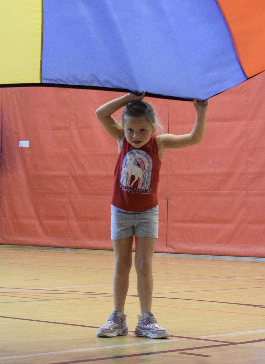 Olivia Carlton, who is 6, is careful not to let go of the parachute.