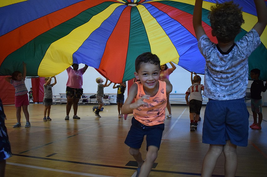 Brody Robinson, who is 4, is thrilled to make it out of the parachute. He laughs as he secures a spot outside the parachute.