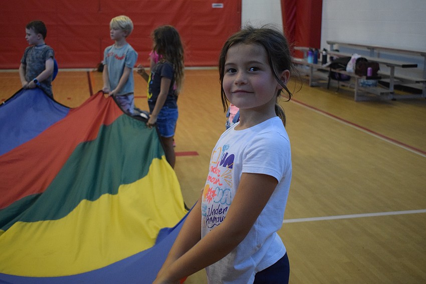 Olivia Corbett, who is 6, holds on tight to the parachute before raising it above her head.