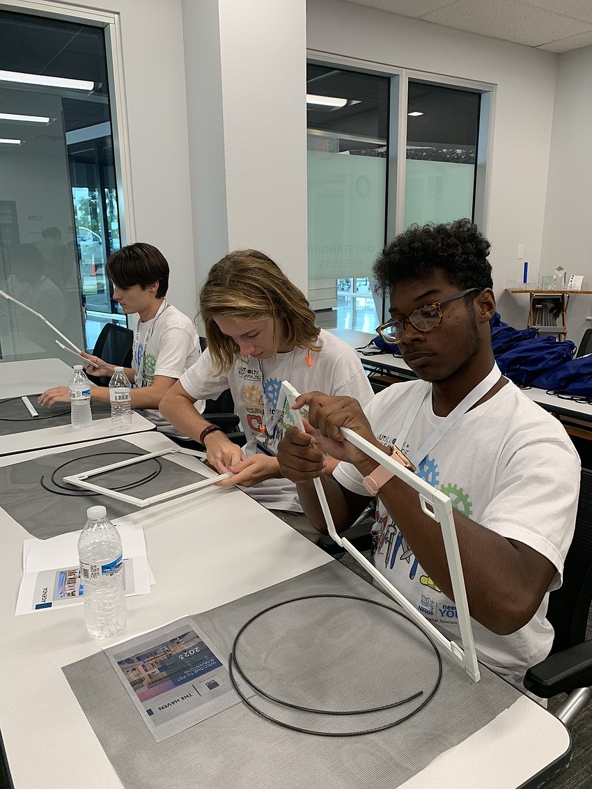 Mark Hornyak, Michael Federici and John Mcclain build their own window screen at PGT Innovations.
