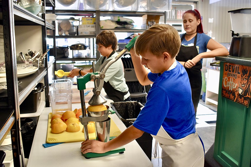 Max Dinetz, 12 years old, and 11-year-old Henry Greenwell make orange juice as Ali Harsey supervises.