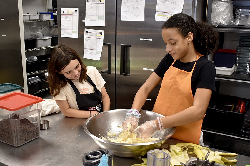 11-year-old Cecilia Antista watches as 11-year-old Makailyn Brown mixes dough.
