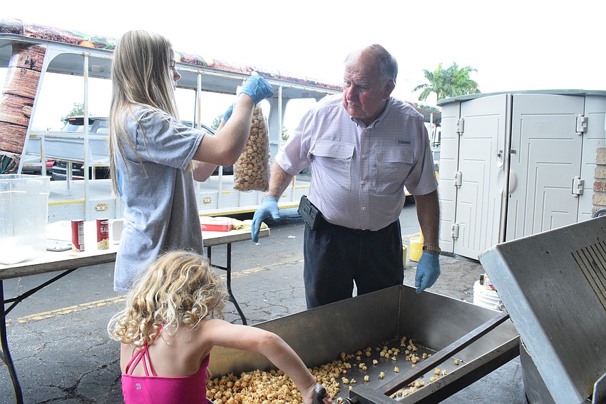 Waverly Busa, who is 4, and Sully Hubert, who is 14, help their grandfather Dean Mixon, the owner of Mixon Fruit Farms, make and bag kettlecorn.