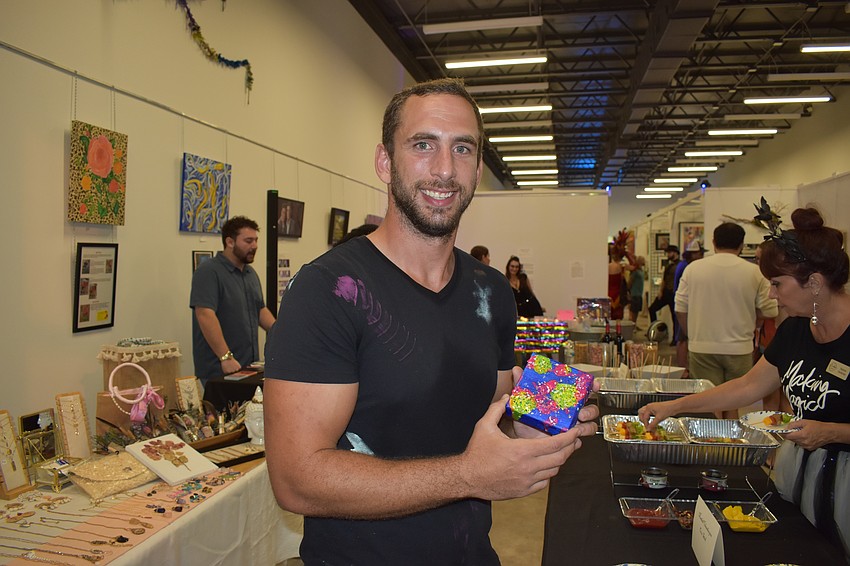 Simon Miken shows the piece of art he purchased from artist Drita Dawn Hajroja.