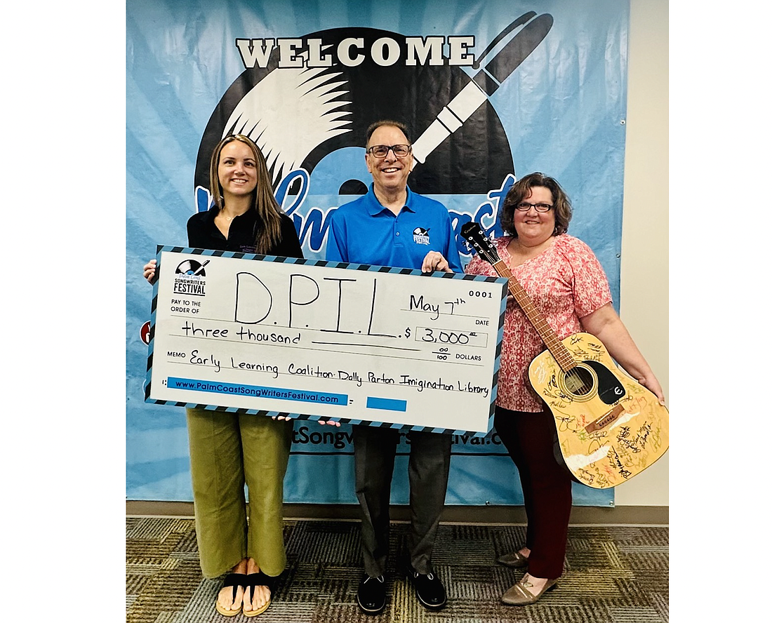 From left to right: Family Services Director Kim Kania with the Early Learning Coalition of Flagler and Volusia, the Dolly Parton Imagination Libray affiliate; Garry Lubi, co-founder and president of the Palm Coast Songwriters Festival; Kelly Wright, the winner of the autographed guitar. Photo courtesy of the Songwriters Festival