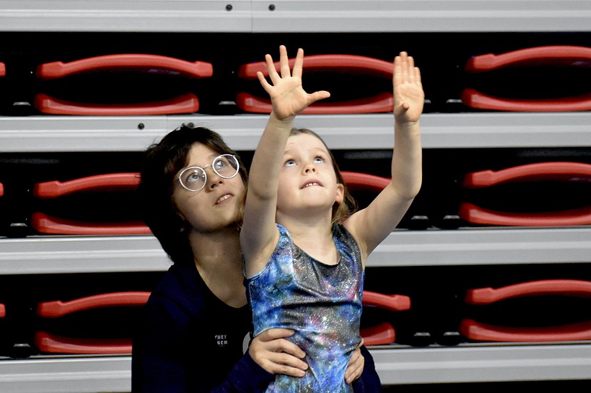 Counselor-in-training Helena Kushner helps 6-year-old Clair Chase reach for a bar.