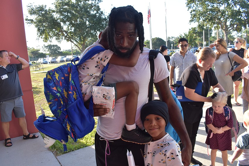 Donnell Livingston has his hands full as he drops off his nephews, kindergartner Kane Smith and first grader Kevin Smith, for the first day at Freedom Elementary.