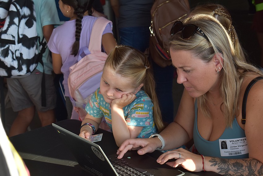 Pre-K student Emery Viergever waits as her mom Jordan Viergever, a PTO volunteer, checks families in before the opening day at Freedom Elementary.