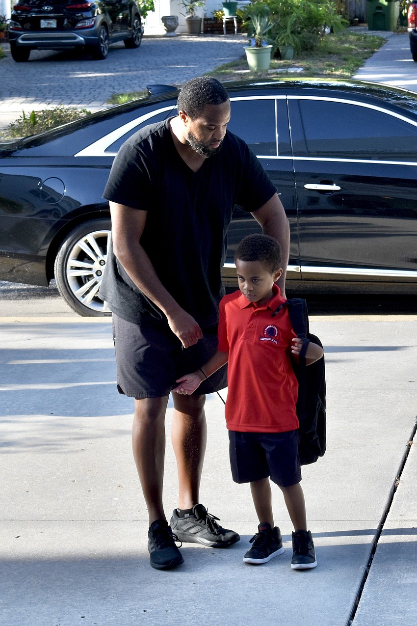 Rashad Sullivan helps Roman Sullivan, 6, with his backpack as they head towards school.