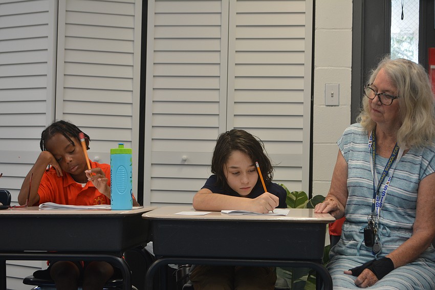 Third graders Noor Furlow and Roger Hernandez work on an assignment with their teacher, Linda Kneeland