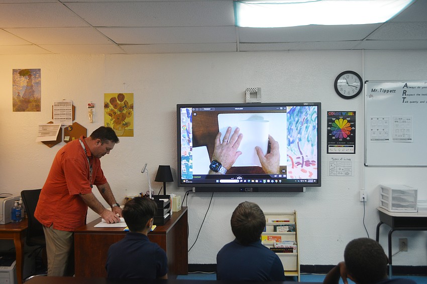 Art teacher Mr. Tippett shows fifth graders how to fold their sketchbooks.
