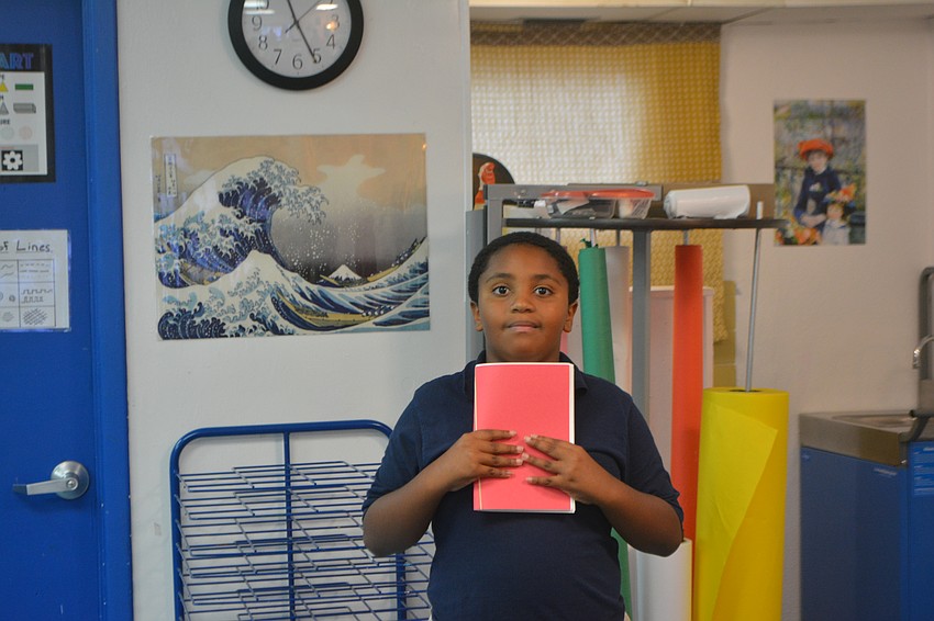 Fifth grader Carmelo Jackson holds up his sketchbook during art class.