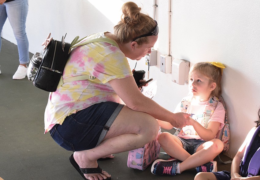 Christine Sharpe has a chat with her daughter Evelynn Sharpe, a kindergartner at Gene Witt Elementary School, before saying goodbye. 