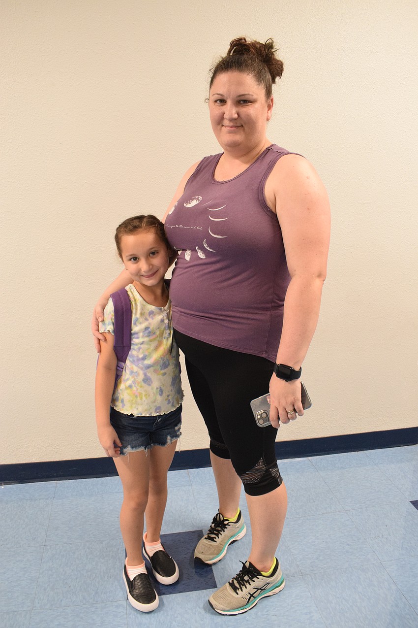 Camille Booth, a second grader at Gene Witt Elementary School, walks to class with her mother, Becca Booth. Camille Booth says she can't wait to get back on the playground for recess.